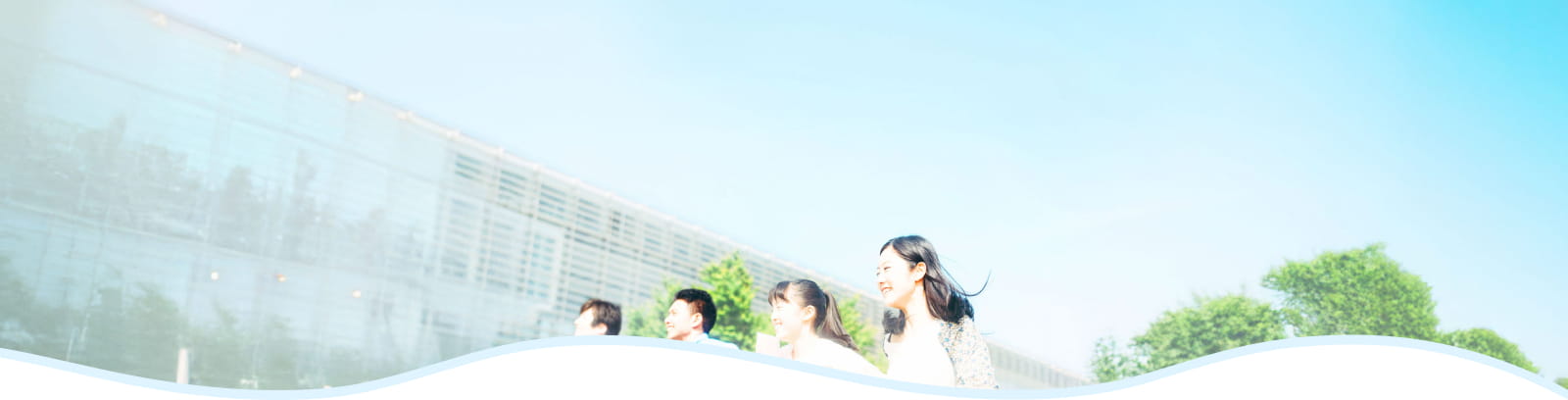 晴れた空の下、若い男女数人が屋外で笑顔で歩いている様子